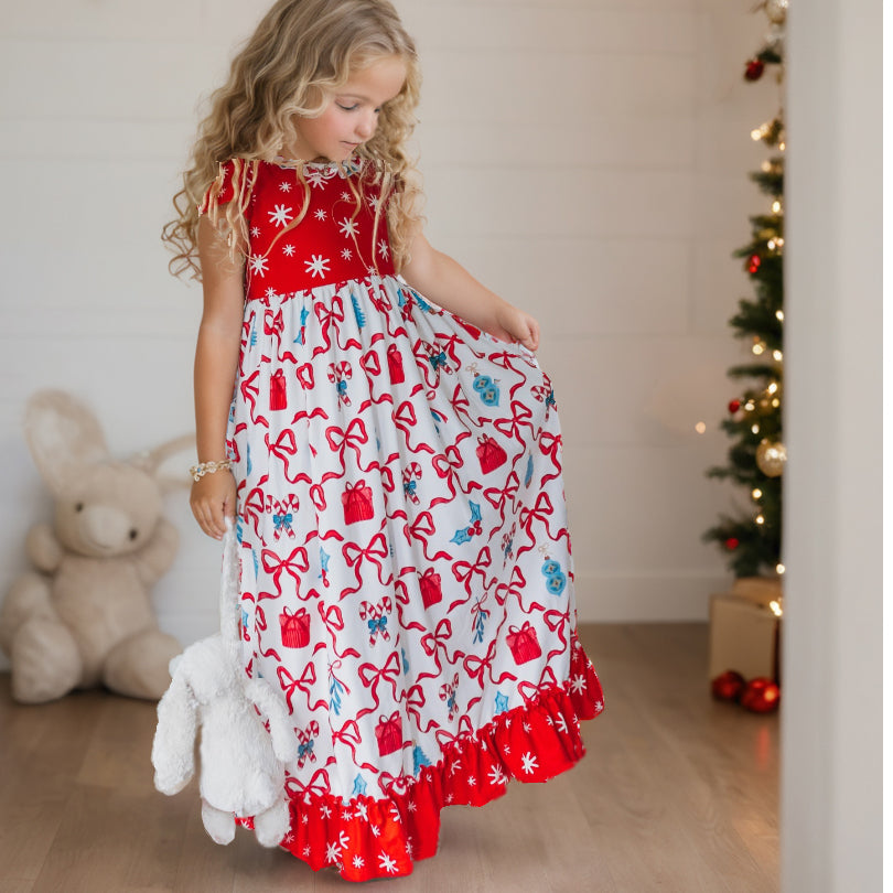 Girl wearing a red and white Christmas lounge gown with festive bow print and red ruffle trim.
