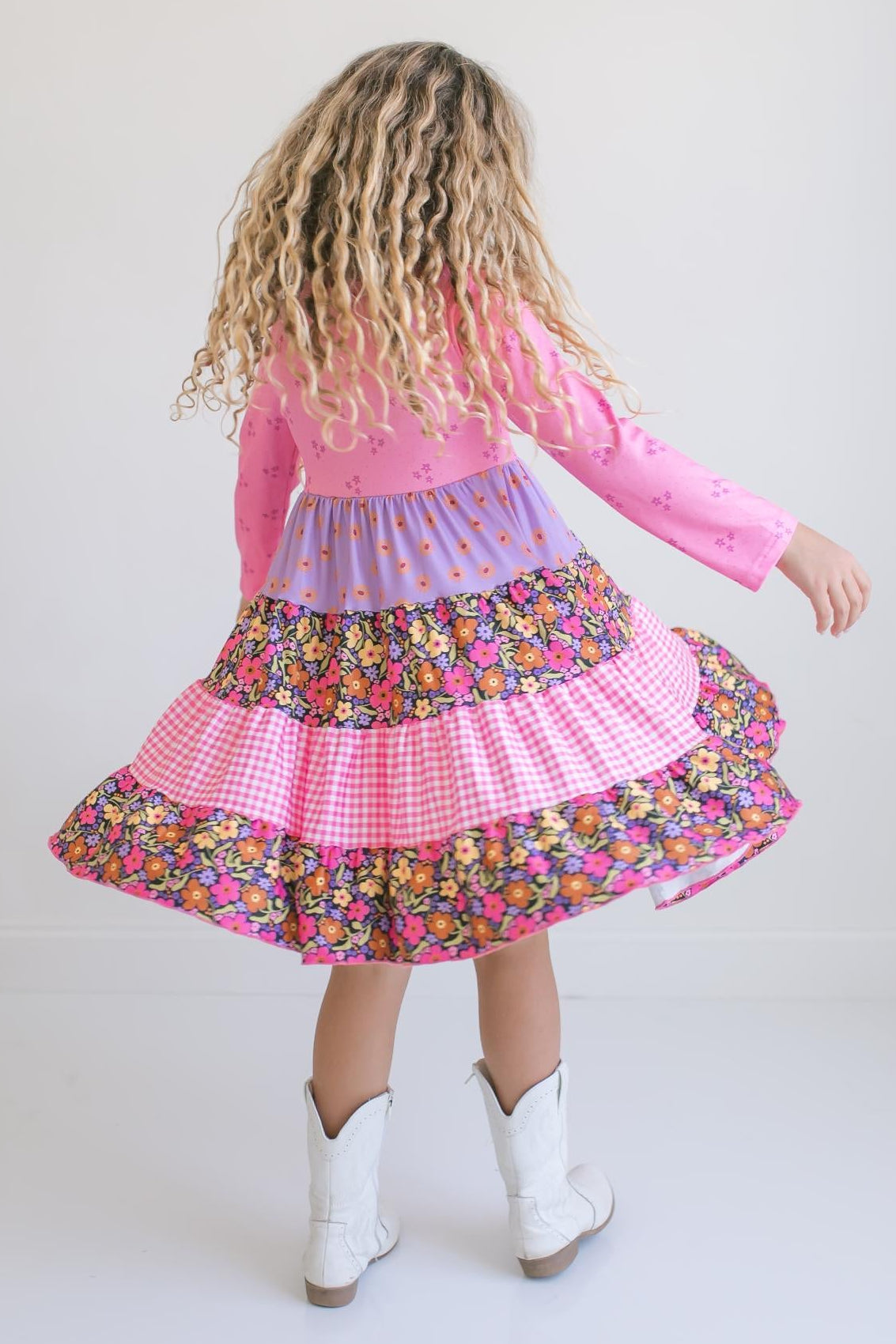 Back view of pink floral long sleeve dress showing colorful layered skirt.
