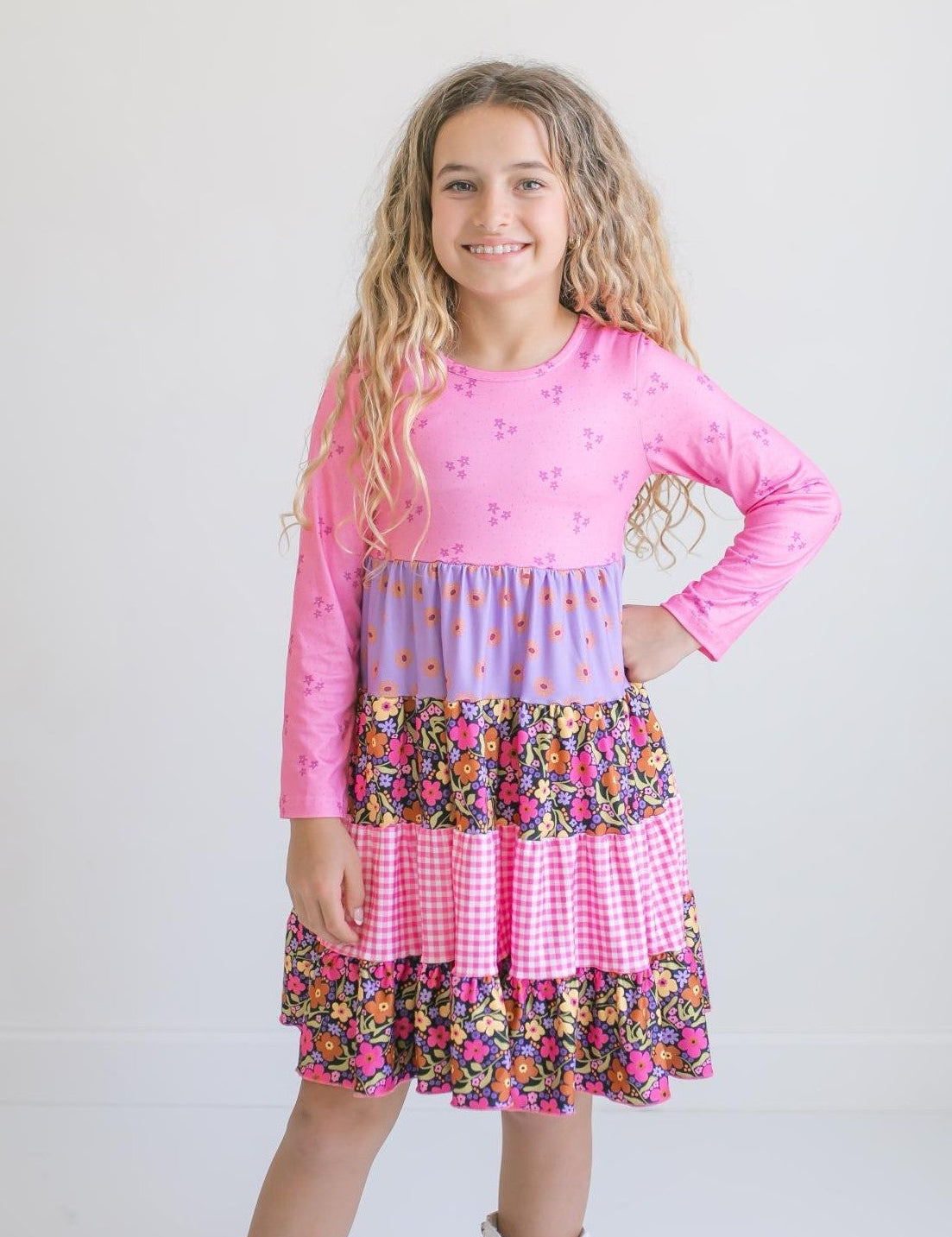 Girl modeling a pink and purple floral dress with gingham accents.