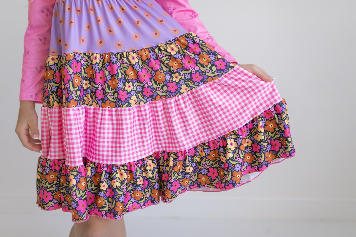 Close-up of pink floral dress showing tiered ruffles and patterned fabric.