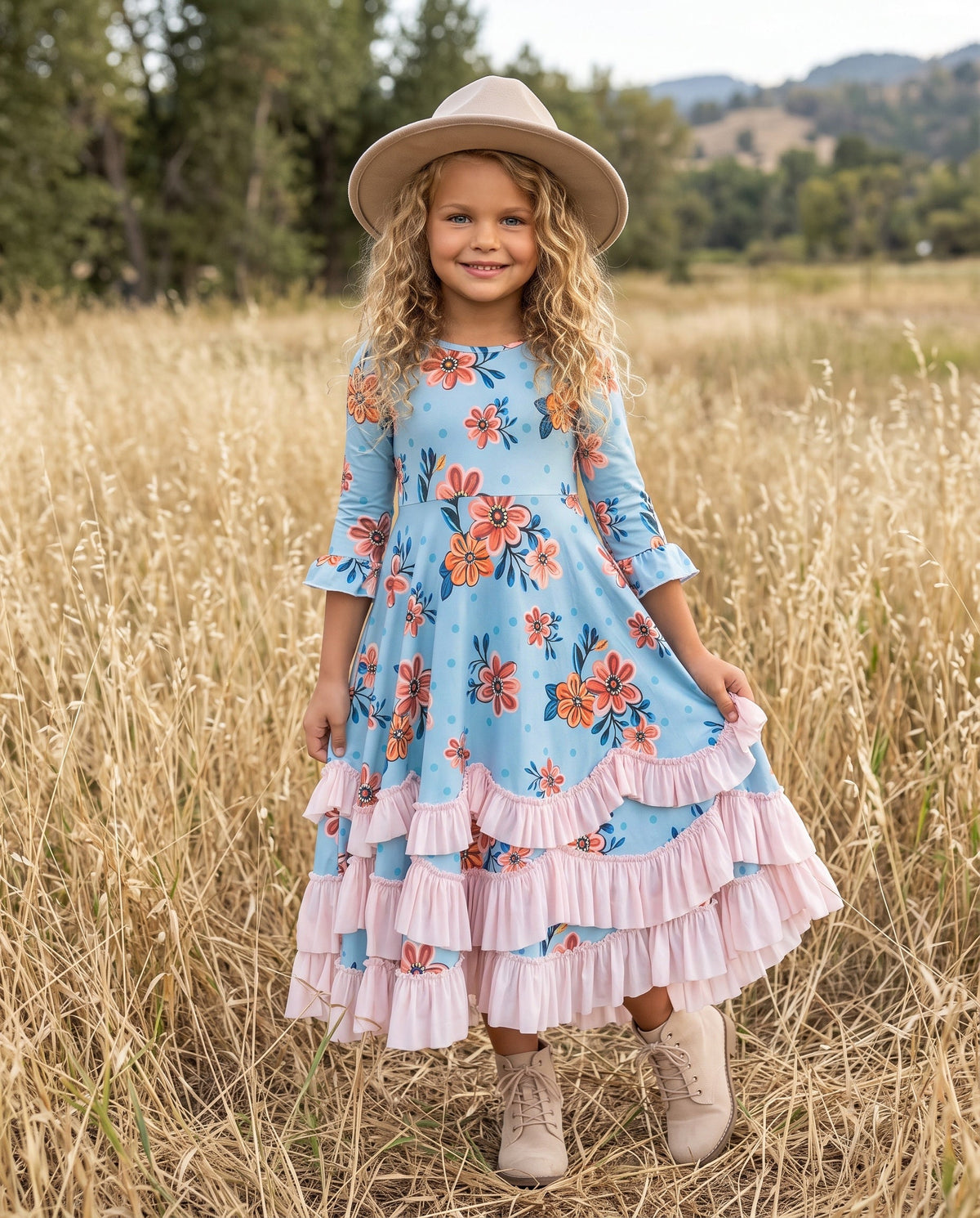 Girl modeling a pastel floral ruffle dress in a grassy field.