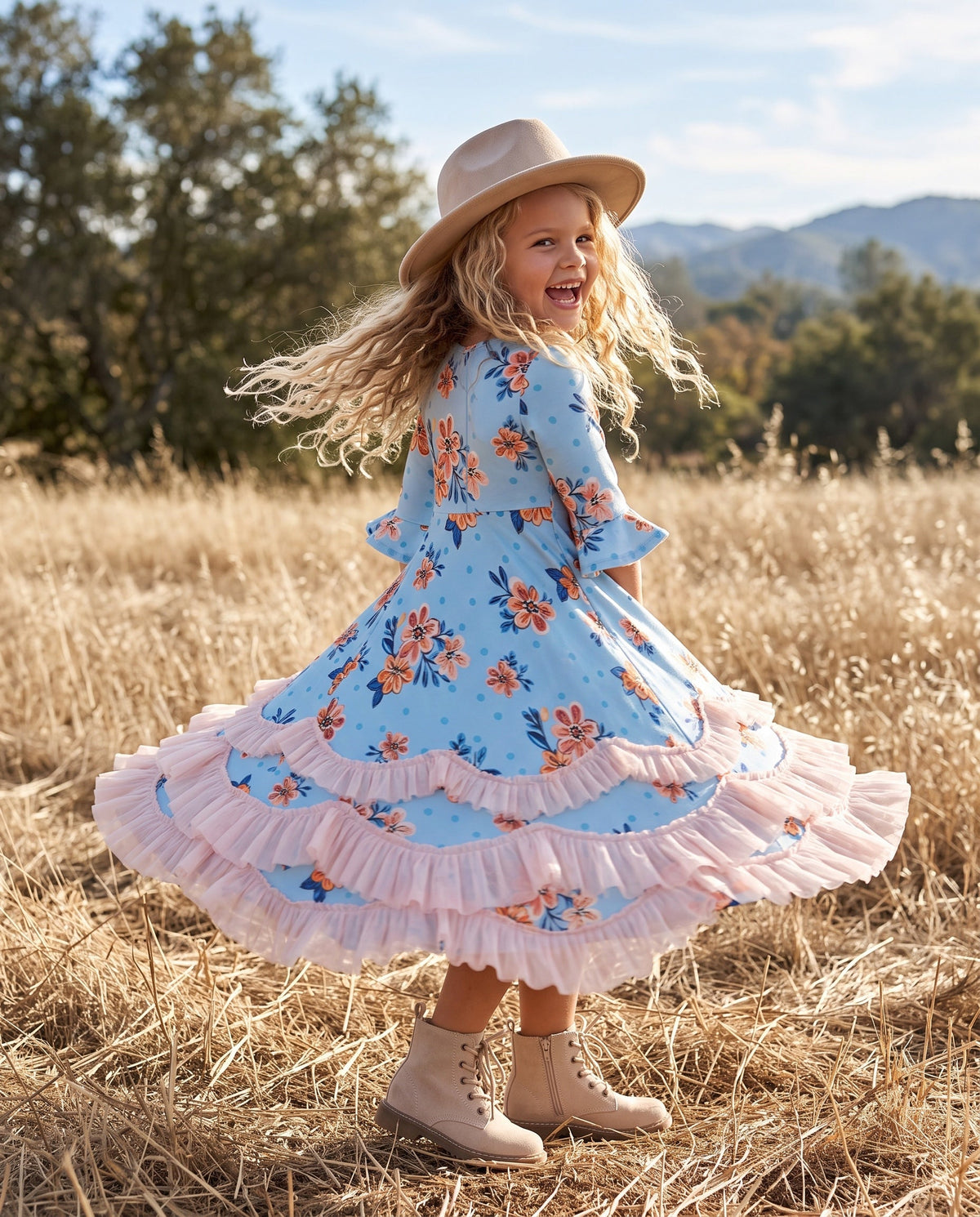 Girl wearing a pastel blue and pink floral ruffle dress while twirling outdoors.