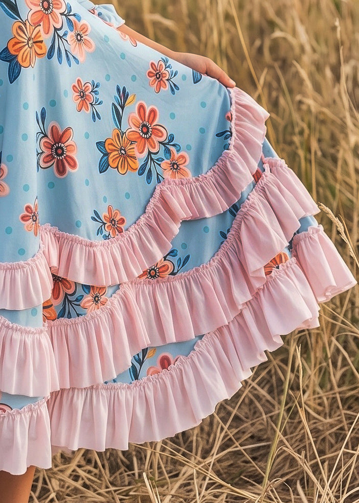 Close-up of pastel floral fabric and colorful ruffle details on girls' dress.