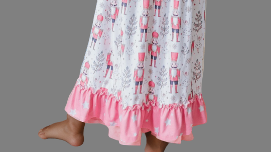 Back view of girls' pink Nutcracker Christmas nightgown featuring a festive holiday print and ruffle trim.