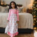 Girl wearing a pink Nutcracker Christmas lounge gown with long sleeves, festive holiday print, and ruffle trim.
