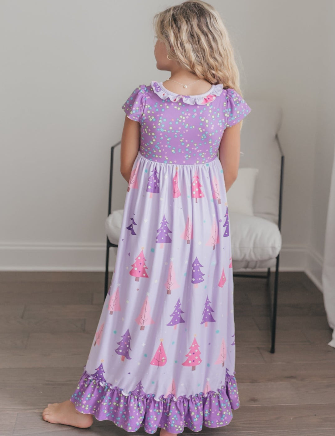 Girl modeling a purple Christmas tree nightgown with festive polka dots.