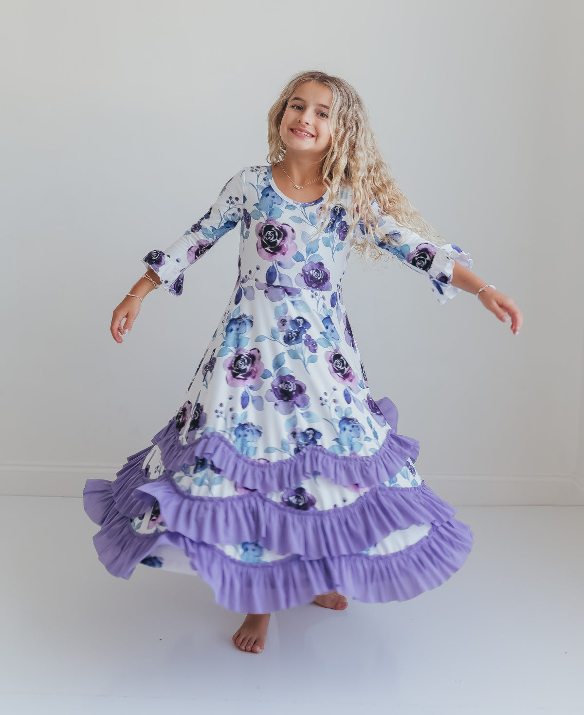 Girl modeling a lavender floral ruffle dress against a plain background.