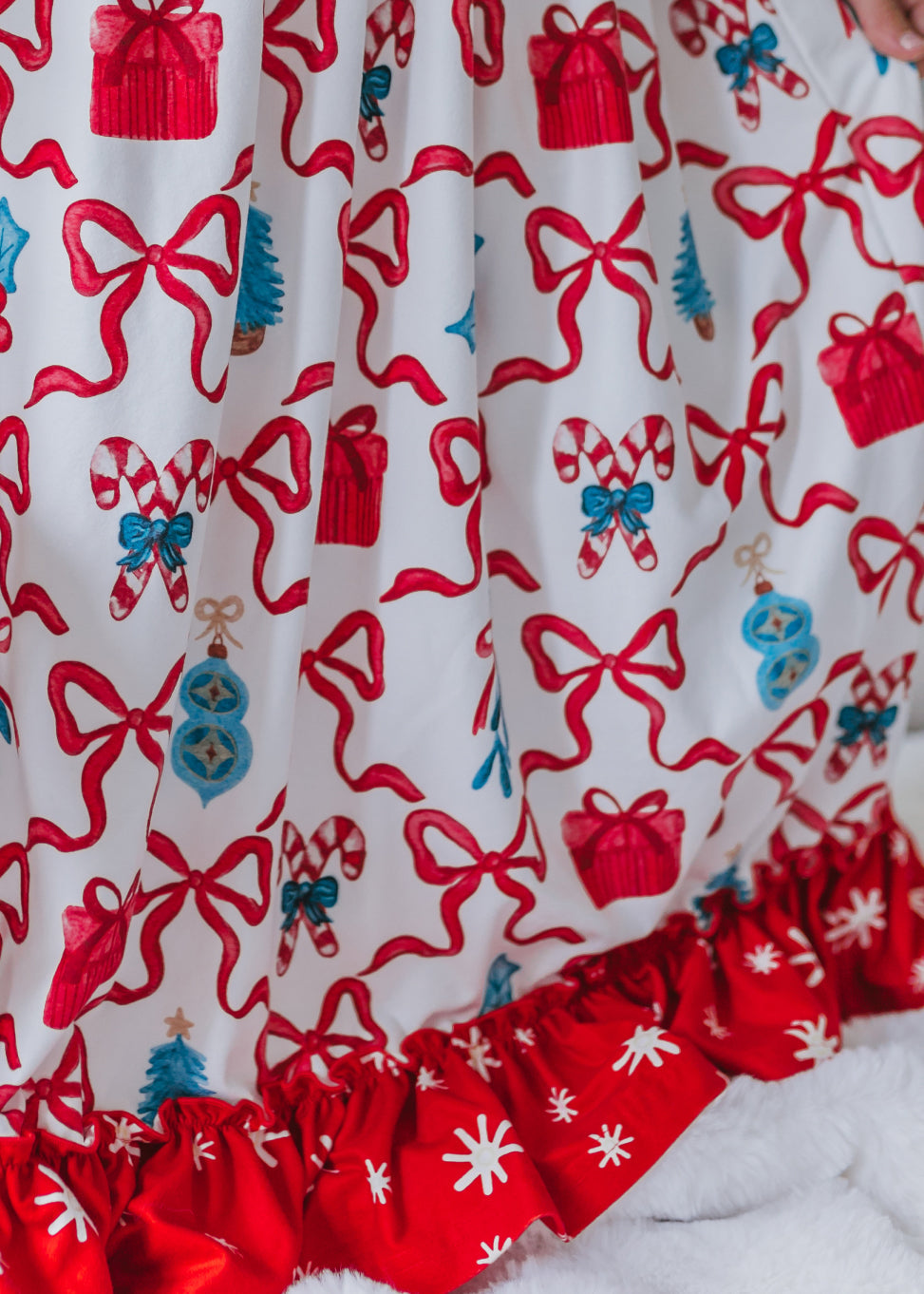 Close-up of red and white Christmas lounge gown fabric featuring festive red bows and holiday-themed print.