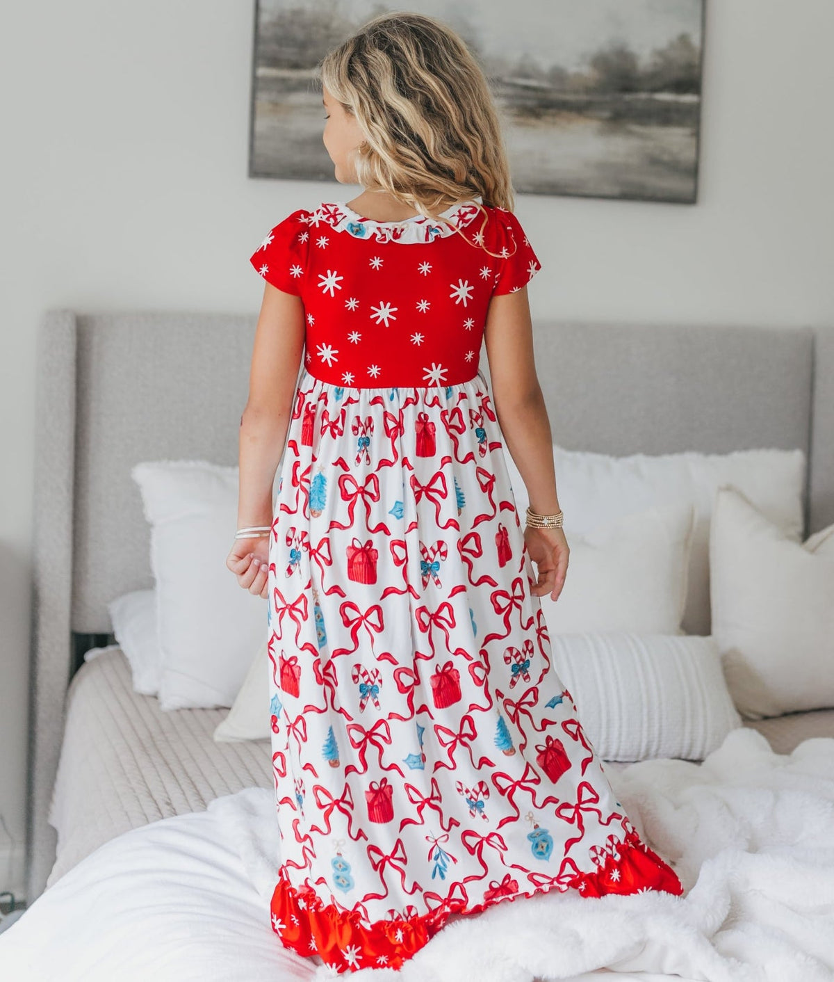 Back view of girls' red and white Christmas lounge gown featuring a festive bow print and red ruffle trim.