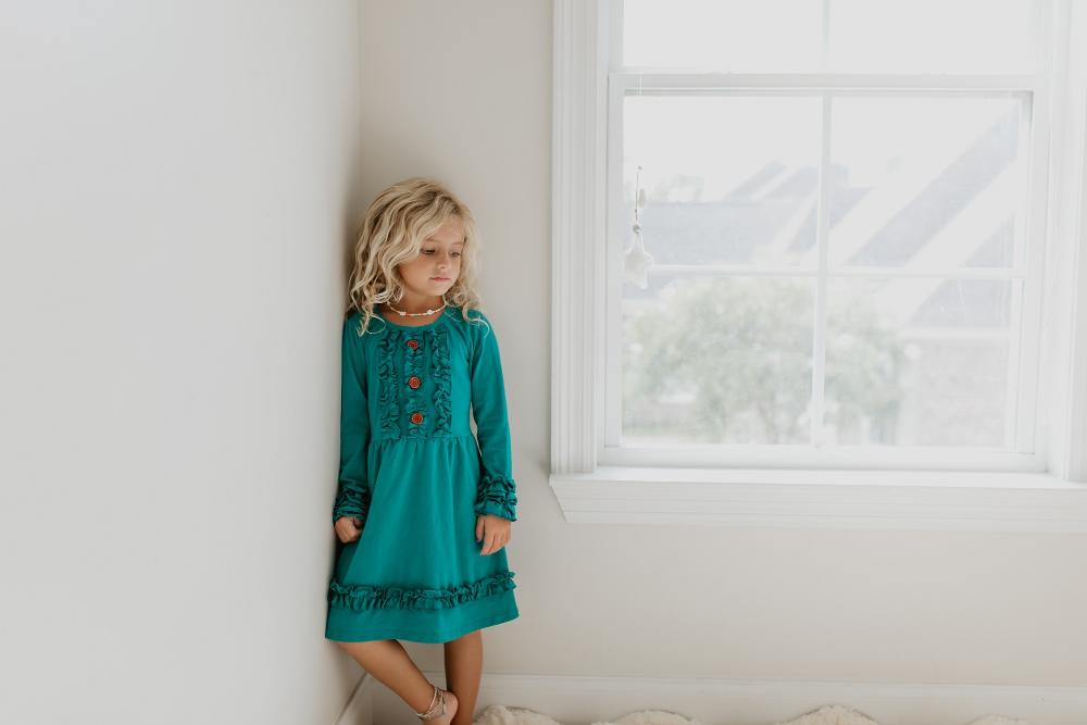 Girl modeling a solid teal green long sleeve dress indoors.