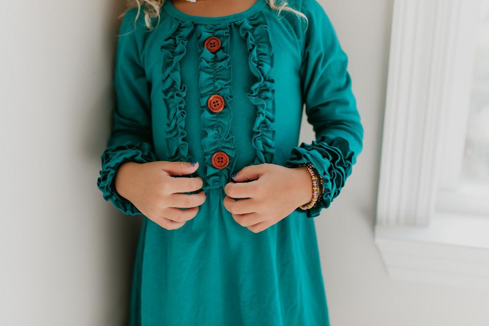 Front view of girls' teal green dress featuring long sleeves and ruffles.