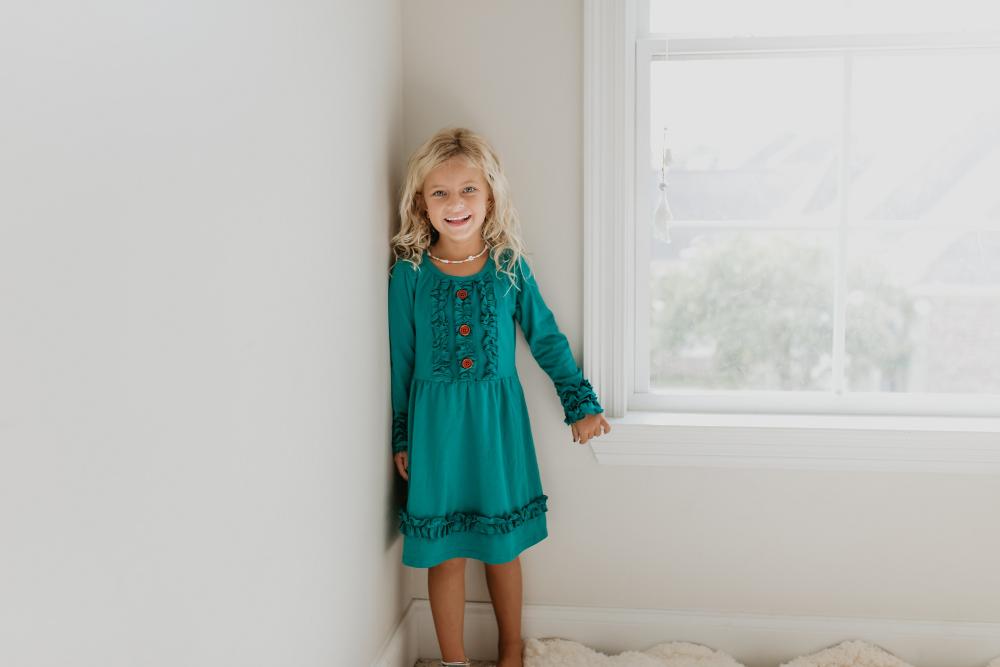Back view of girls' solid teal green dress showing its silhouette.