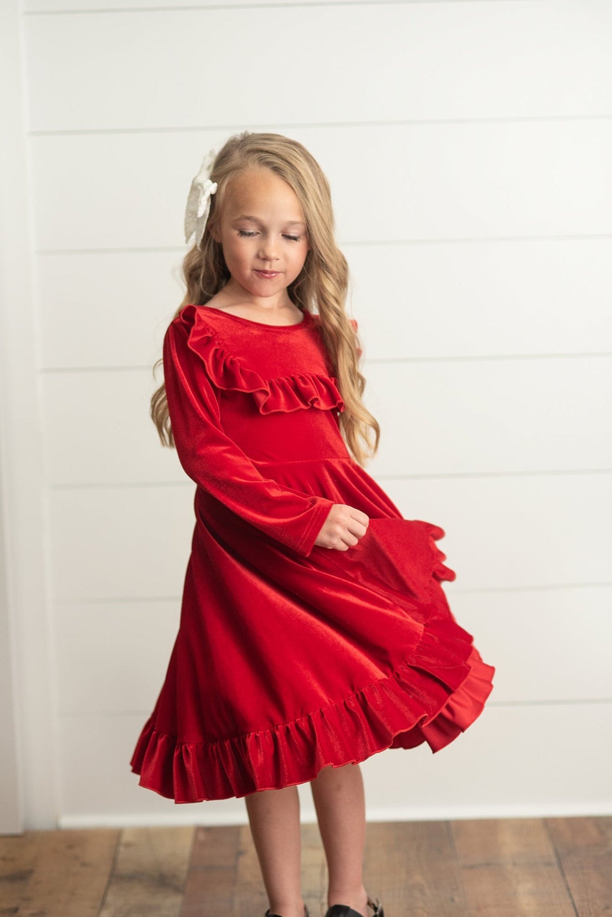 
Girl wearing a red Christmas dress with long sleeves and flowing skirt.