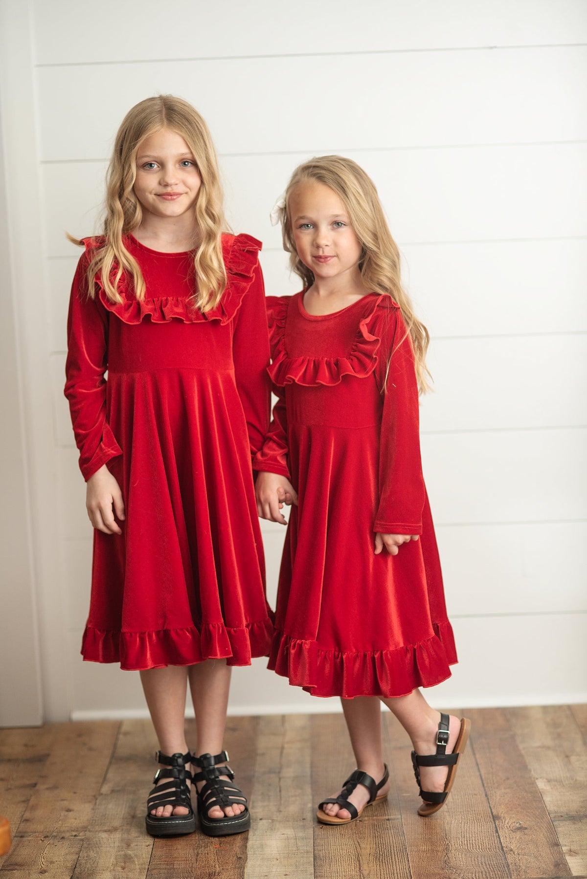 Girls wearing matching red dresses for holiday photos.