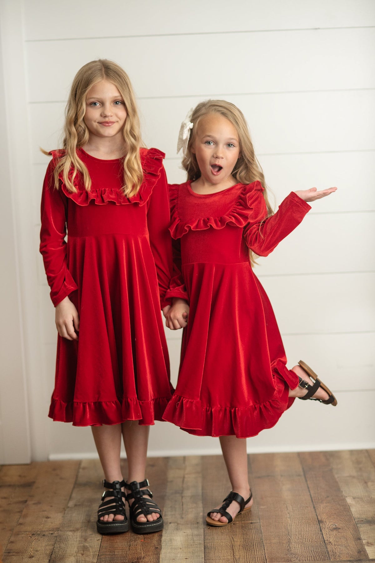 Two girls wearing red holiday dresses with flowing skirts.