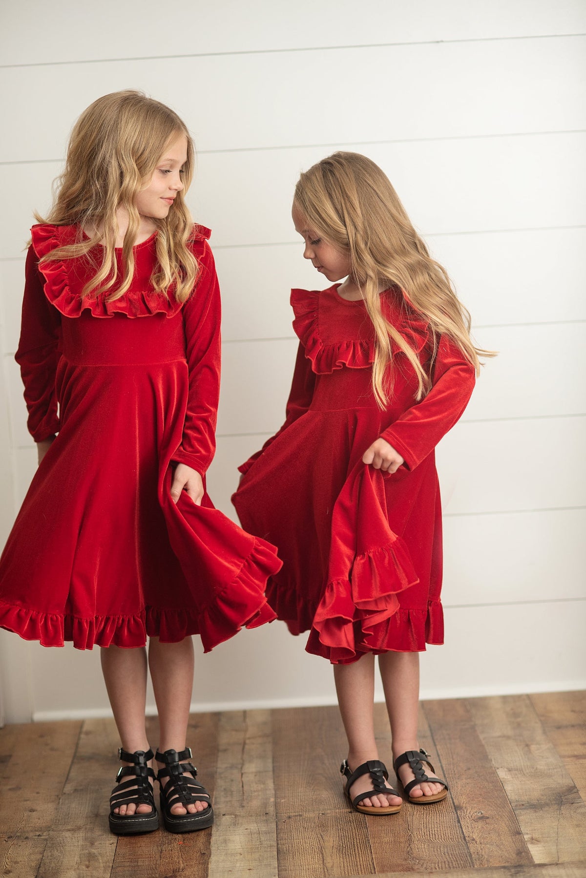 Girls modeling matching red holiday dresses for Christmas.